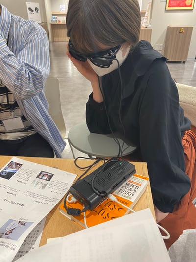 【写真】弱視の方が「レティッサディスプレイ2」をかけて手元の資料を読む様子
