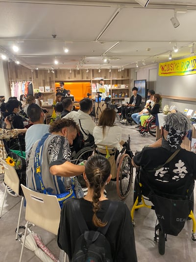 【写真】イベントの様子（20名程がミライロハウスに集まり、登壇者の話を聞く様子。車いすユーザーも数名参加。）