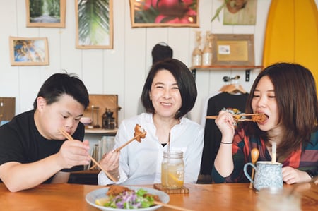 母と娘と息子が笑顔で食事している様子