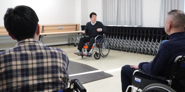 （写真）車いす実技で車いすの説明を行っている様子
