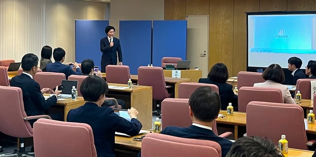 （写真）会場の前で男性がマイクを持って話している様子