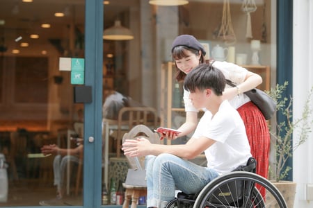 車椅子ユーザーの人と、車椅子ユーザーでない人が一緒に移動する様子