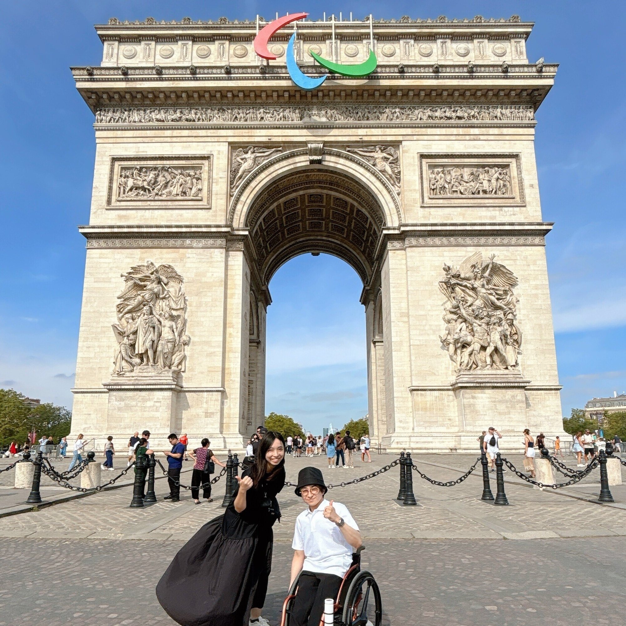 （写真）パリの凱旋門の前で社員と社長が前を向いている様子