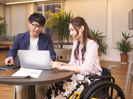 写真 車いすユーザーとユーザーでない人が一緒に仕事をする様子
