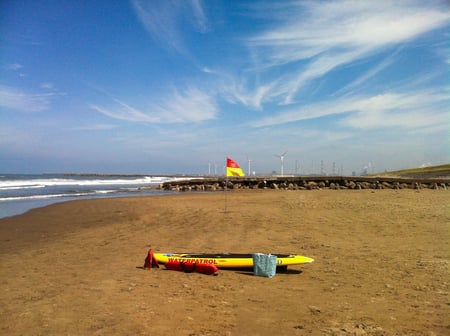 写真　砂浜に立つ黄色と赤で構成された旗