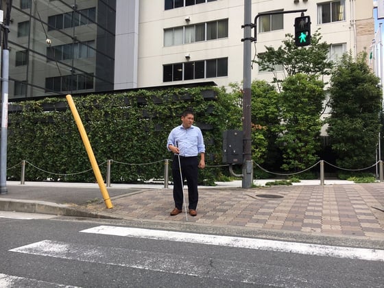 画像　白杖を持ち横断歩道を歩く原口