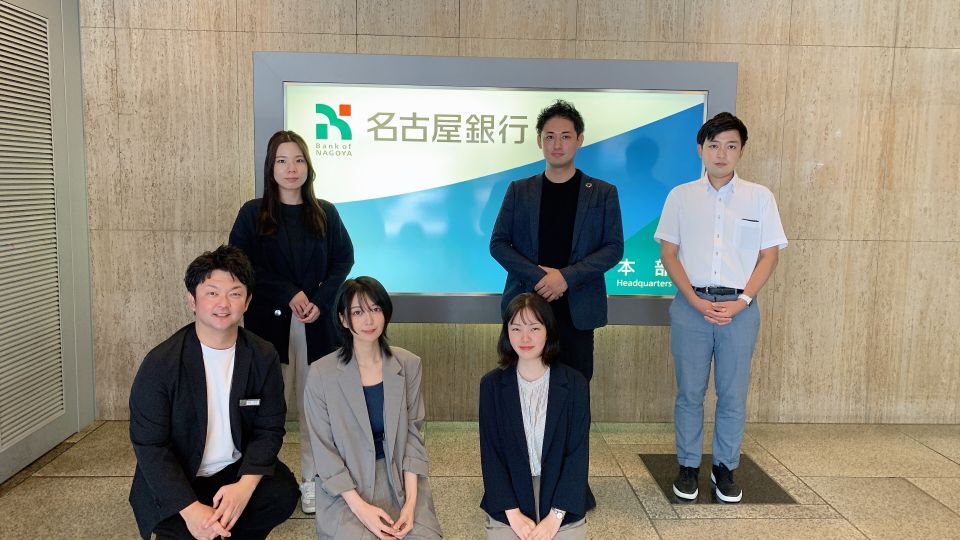 名古屋銀行の社員の方たち6名が名古屋銀行の看板の前で撮影