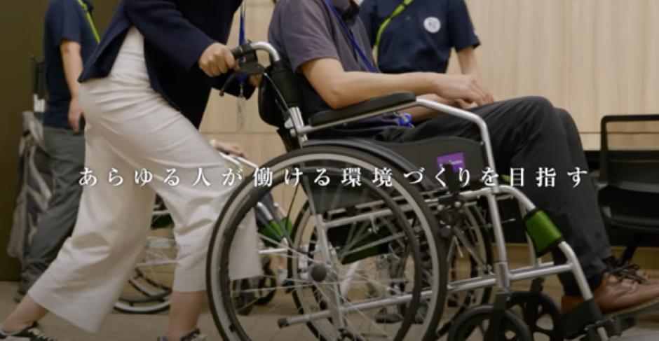 車いすに乗っている人をサポートしている写真とキャッチコピーあらゆる人が働ける環境づくりを目指す